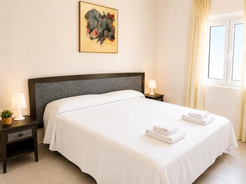 a bedroom with a white bed with two towels on it at Apartamentos Larga 70 in El Puerto de Santa María
