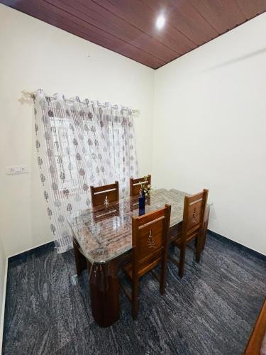 a dining room with a table and wooden chairs at Palm paradise in Kadavoor