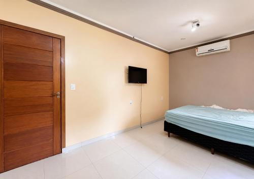 a bedroom with a bed and a tv on the wall at Pousada Miriam in Limeira