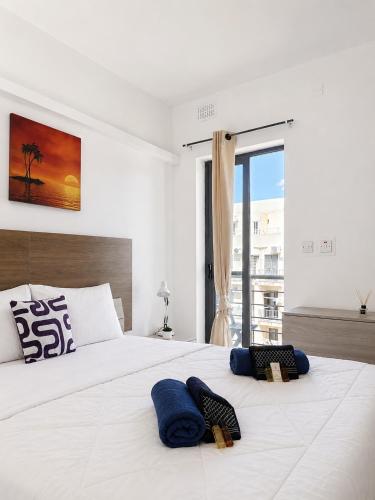 a bedroom with a large white bed with blue pillows on it at Central Msida Modern Holiday Apartment in Tal-Ħriereb