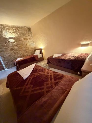 a bedroom with two beds and a stone wall at Mawasem Dana in Dana