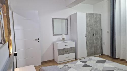 a white bedroom with a mirror and a dresser at Emi Center Apartments in Gevgelija