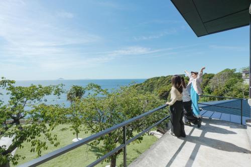 two people standing on a balcony overlooking the ocean at 河津Blue Ocean in Kawazu