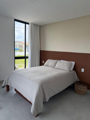 a bedroom with a large bed and a large window at Condomínio Bosque da Praia, casa 193 Jacumã RN in Jacumã