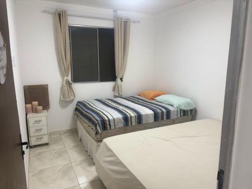 a small bedroom with a bed and a window at Casa espaçosa em Itacimirim com piscina e churrasqueira! in Camaçari