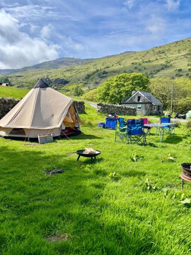 a tent and a table and chairs in a field at Wild Camping Teepee in Capel Curig