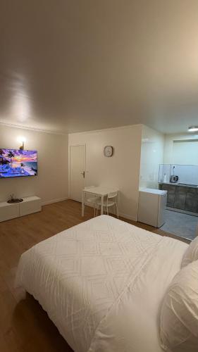 a bedroom with a large white bed and a kitchen at Studio Moderne - Proche 15mn Orly et 25mn Paris in Juvisy-sur-Orge