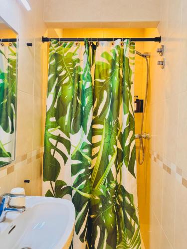 a bathroom with a green leafy shower curtain and a sink at Nanit Rooms Ibiza Hostal in Santa Eularia des Riu