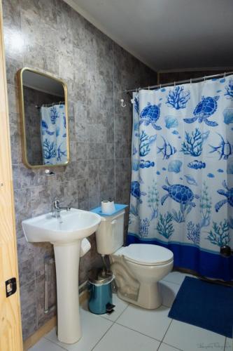 a bathroom with a sink and a toilet and a shower curtain at Hostal Urenda in Los Ángeles