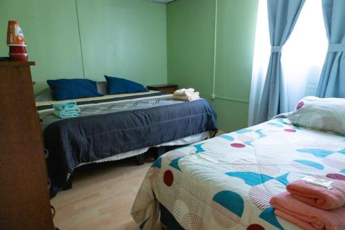 a bedroom with two beds and a window at Hostal Urenda in Los Ángeles