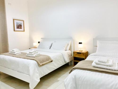 two beds in a bedroom with white sheets and towels at Corso 42 in Novara