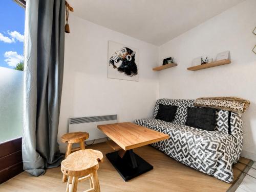 a living room with a couch and a table at Le refuge des sportifs - studio cosy jardin - wifi in Mijoux