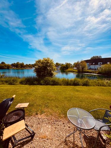 a picnic table and chairs with a view of a river at Barneys Retreat - Lakeside Getaway in South Cerney