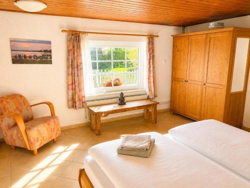 a bedroom with two beds and a chair and a window at Reetdachtraum in Middelhagen