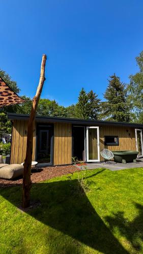 a house with a tree in the yard at Panterhuis Leo l Tiny House l Buitenbad, airco, speeltuin, bostuin in Epe
