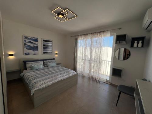 a bedroom with a bed and a large window at Pergola Penthouse Xaghra in Xagħra