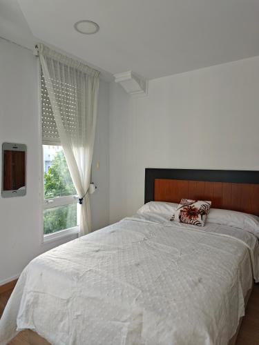 a bedroom with a large white bed with a window at Apartamento Leal Ferrol in Ferrol