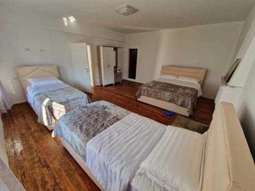 two beds in a room with wooden floors at Bujtina Dalmacia in Shkodër