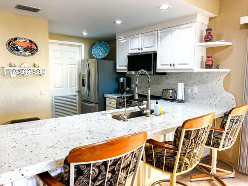 a kitchen with a counter with chairs and a sink at Sandy Beach Princesa B309 Ocean Front Resort in Puerto Peñasco