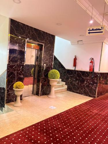 a lobby with two vases and a fire extinguisher at Asus Al Taj Serviced Apartments in Baish