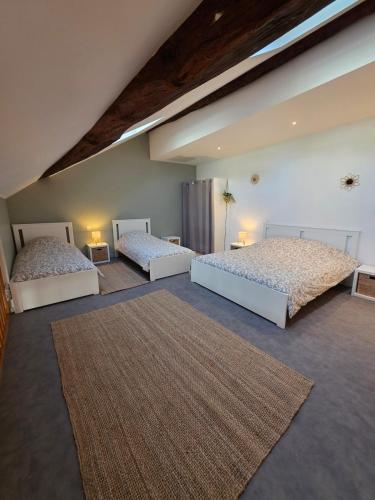 a bedroom with two beds and a rug at L'Écrin Historique - Duplex - Vieux Chaumont in Chaumont