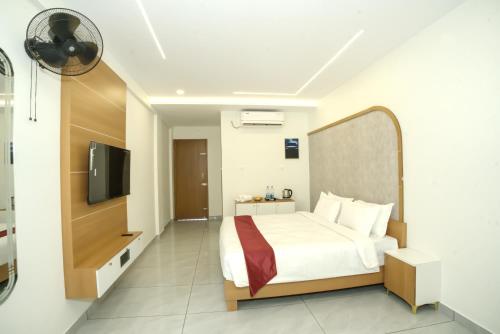 a bedroom with a bed and a flat screen tv at UK Plaza in Edappāl