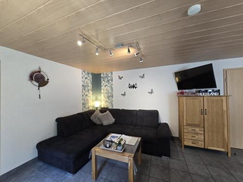 a living room with a black couch and a table at Haus Blume in Medebach