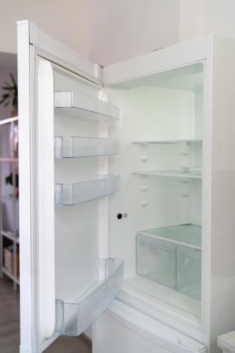 a white refrigerator with its door open at Interior Apartments - Service Apartments in Bahnhofsnähe und UNESCO-Bergpark mit Parkplatzmöglichkeit, EBK, kinderfreundlich, Familienzimmer in Kassel