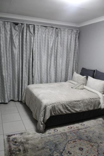 a bedroom with a bed and a window with curtains at Penthouse in Bloemfontein