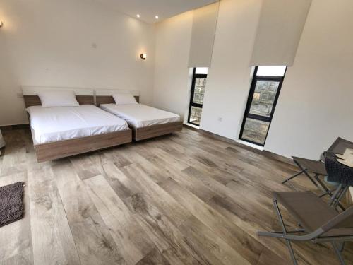 a bedroom with a bed and wooden floors and windows at شالية الشفق in Al ‘Aqar
