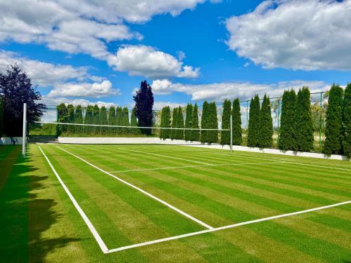 a tennis court with a net on a field at Rezydencja Florina - Willa z prywatnym basenem, jacuzzi i kortem tenisowym in Rogóźno