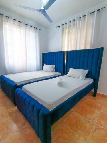two beds in a room with blue furniture at Bella Accomodations, Mombasa in Bamburi