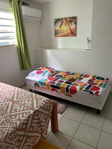 a bedroom with a bed with a colorful comforter at Le Havre de paix in Le Robert
