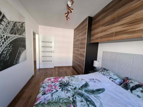a bedroom with a king sized bed with a wooden headboard at Apartament Rekiny na Wakacjach - Aquapark Reda 200m - Prywatny Parking in Reda