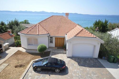 a black car parked in front of a house at Apartment Beachfront Petar in Zadar