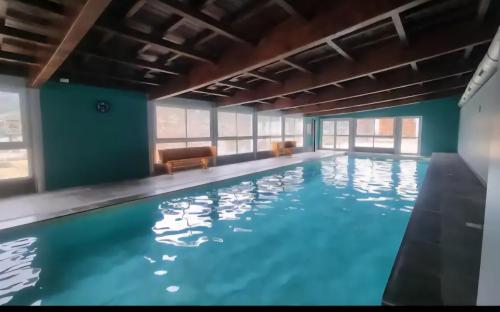 a large indoor swimming pool with blue water at Cocon cosy et spa au Château des Magnans Jausiers in Jausiers