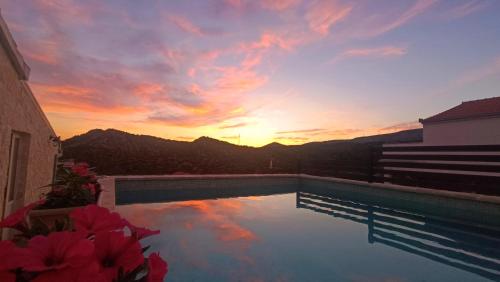 a swimming pool with a sunset in the background at Apartment Igralište Mirakul in Seget Vranjica