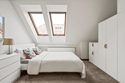 a white bedroom with a bed and two windows at Willa Horyzont in Hel