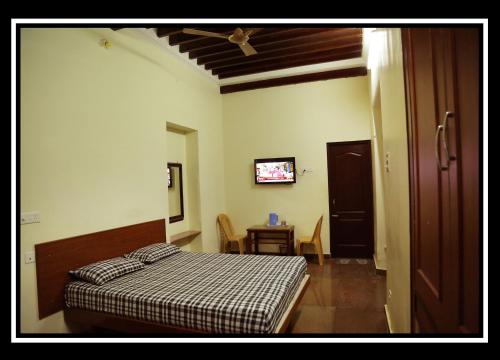 a bedroom with a bed and a table and a tv at Pattiah Naidu Palace in Palani