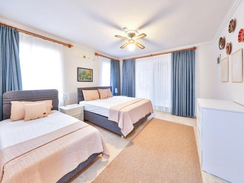 a bedroom with two beds and a ceiling fan at Villa Defne Kaş in Cukurbag