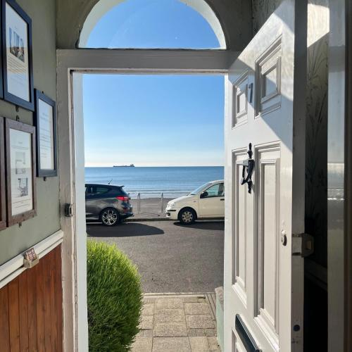 an open door to a parking lot with a view of the ocean at Whitecliff Guest House in Weymouth