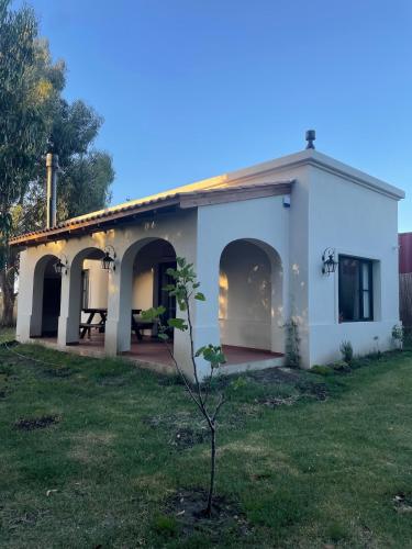 a small white house with a table in a yard at Casita colonial en Chapadmalal in Chapadmalal