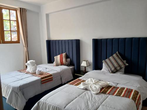 two beds in a room with blue and white at Pinkuylluna Lodge in Ollantaytambo