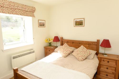 a bedroom with a bed with two lamps and a window at The Wee Bothy at East Lothian Cottages in Lennoxlove