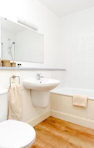 a white bathroom with a sink and a bath tub at The Wee Bothy at East Lothian Cottages in Lennoxlove