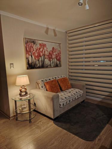 a bedroom with a couch and a table with a lamp at Departamento Los Poetas in Temuco