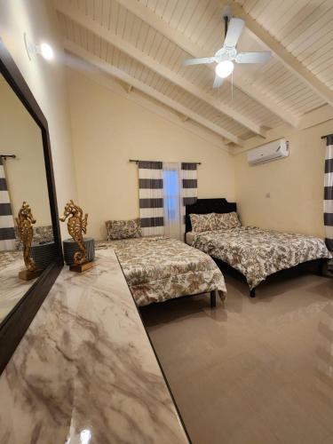 a room with two beds and a ceiling fan at Honeycomb Oceanview Villa in Falmouth