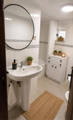 a white bathroom with a sink and a mirror at Casa D'os Eiras in Aguiar da Beira