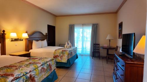 a hotel room with two beds and a flat screen tv at Telamar Resort in Tela