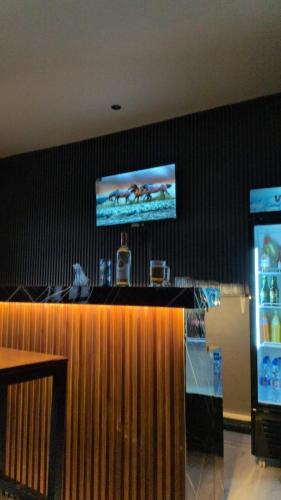 a bar in a restaurant with a tv on the wall at Nyumbani Executive Lodge in Ilala